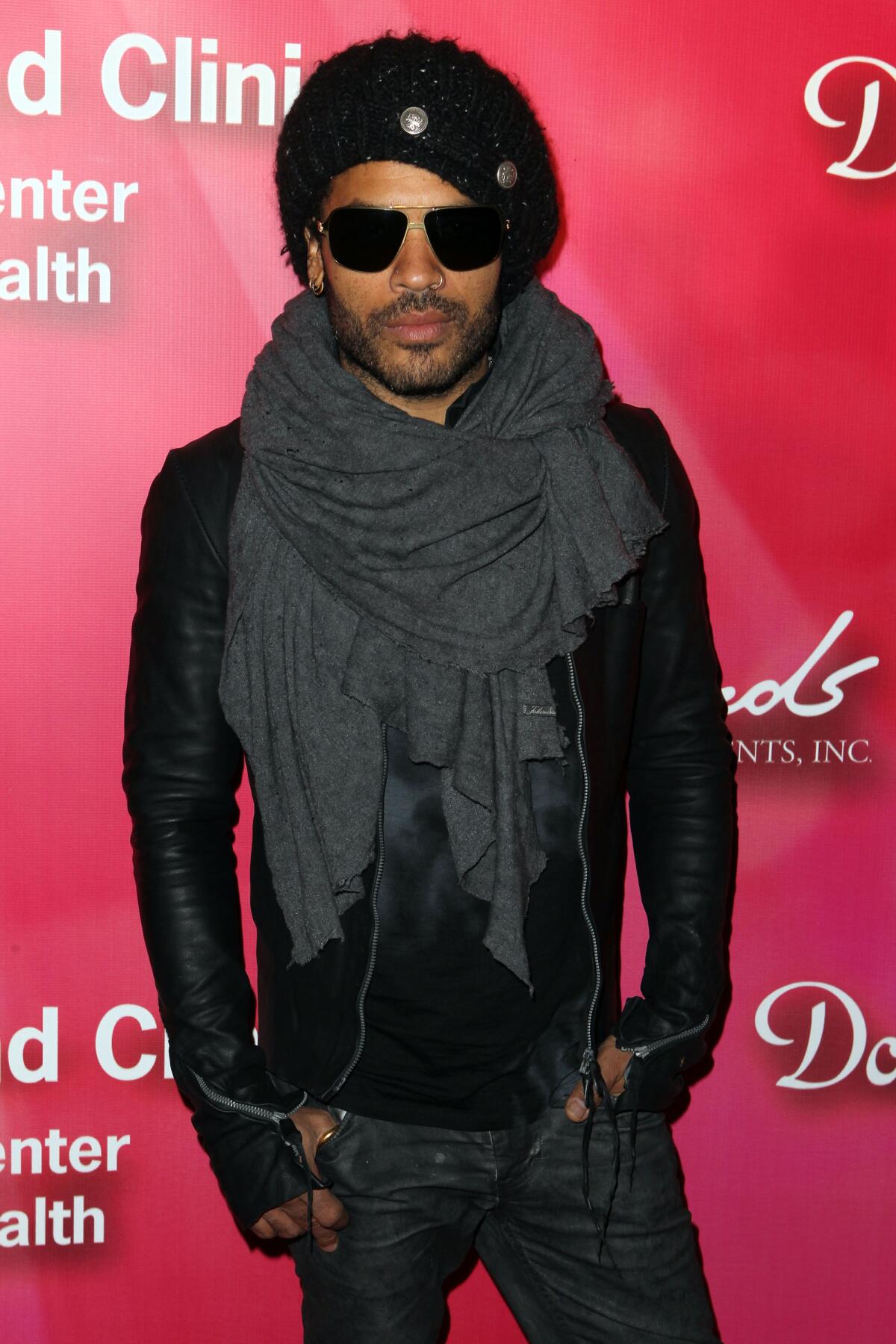 Lenny Kravitz in sunglasses, beret, Jacket with zippers and a large scarf.