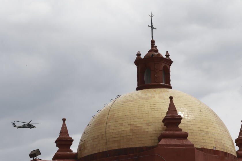 Un helicóptero del ejército mexicano sobrevuela la cúpula de una iglesia