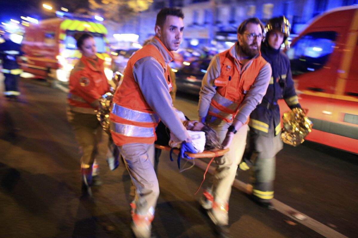 FILE - In this Nov. 13, 2015, file photo, a woman is evacuated from the Bataclan concert hall after a shooting in Paris. In an enormous custom-designed chamber, France is putting on trial 20 men accused in the Nov. 13, 2015, Islamic State terror attacks on Paris that left 130 people dead and hundreds injured. Nine gunmen and suicide bombers struck within minutes of each other at the national soccer stadium, the Bataclan concert hall and restaurants and cafes. Salah Abdeslam, the lone survivor of the terror cell from that night is among those being tried for the deadliest attack in France since World War II. (AP Photo/Thibault Camus, File)