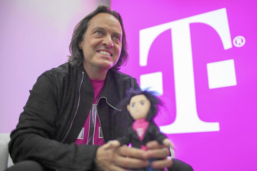 T-Mobile CEO John Legere holds a doll made in his likeness during a media event in San Francisco. Legere has lifted T-Mobile’s flagging customer base and its reputation in unconventional ways.