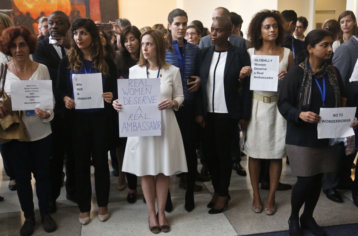 United Nations staff, some holding signs, stand in a silent protest against naming Wonder Woman a U.N. ambassador.
