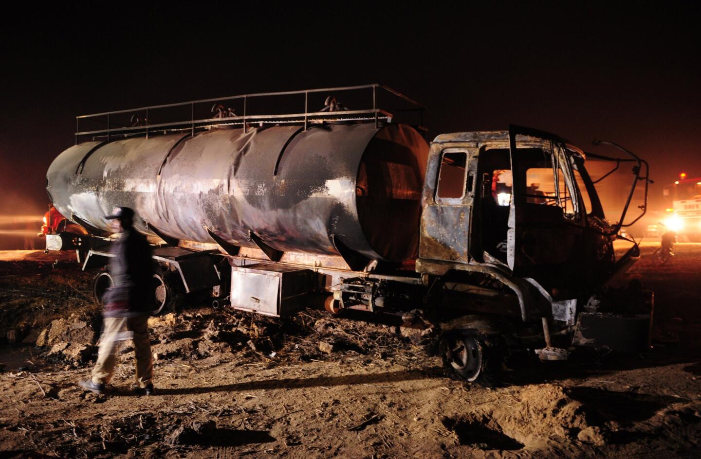 A Pakistani policeman examines a burned oil tanker that hit a passenger bus on a highway near Karachi.