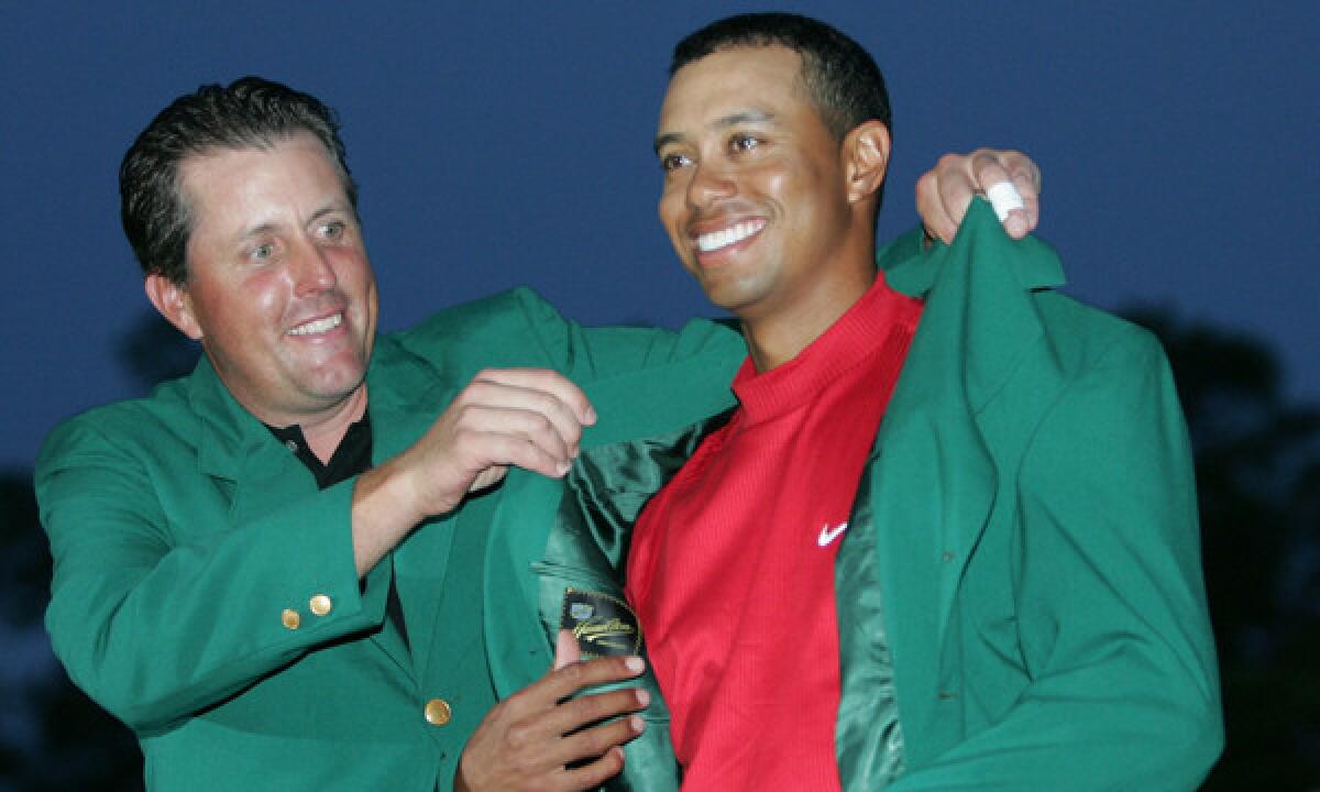 Tiger Woods, right, receives the green jacket from Phil Mickelson after winning the 2005 Masters. Woods won't be wearing the green jacket this year, but his once impressive mid-April runs at Augusta National Golf Club had a ripple effect on the Toyota Grand Prix of Long Beach.