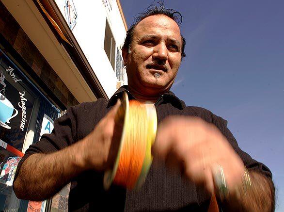 Basir Beria, 47, uses a spool to reel in his handmade kite string -- cotton thread coated with glass -- while flying a fighter kite in front of his store in North Hollywood. The expert kite flyer is from Kabul, Afganistan, where kite fighting has a long tradition. Beria, who came to the United States in 1984, served as kite master on the recent film "The Kite Runner."