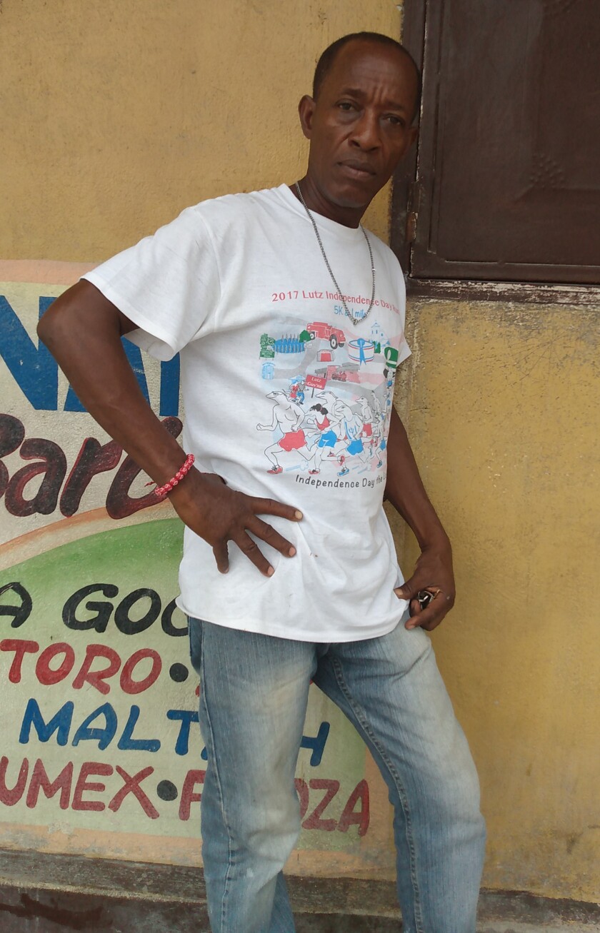A man in a white T-shirt and jeans has one hand on his hip