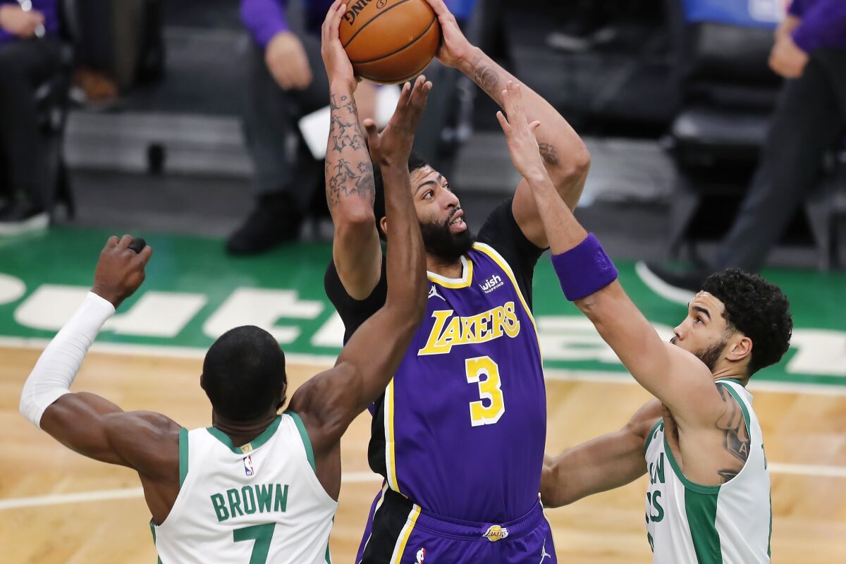 The Lakers' Anthony Davis shoots between the Celtics' Jaylen Brown and Jayson Tatum on Jan. 30, 2021, in Boston.