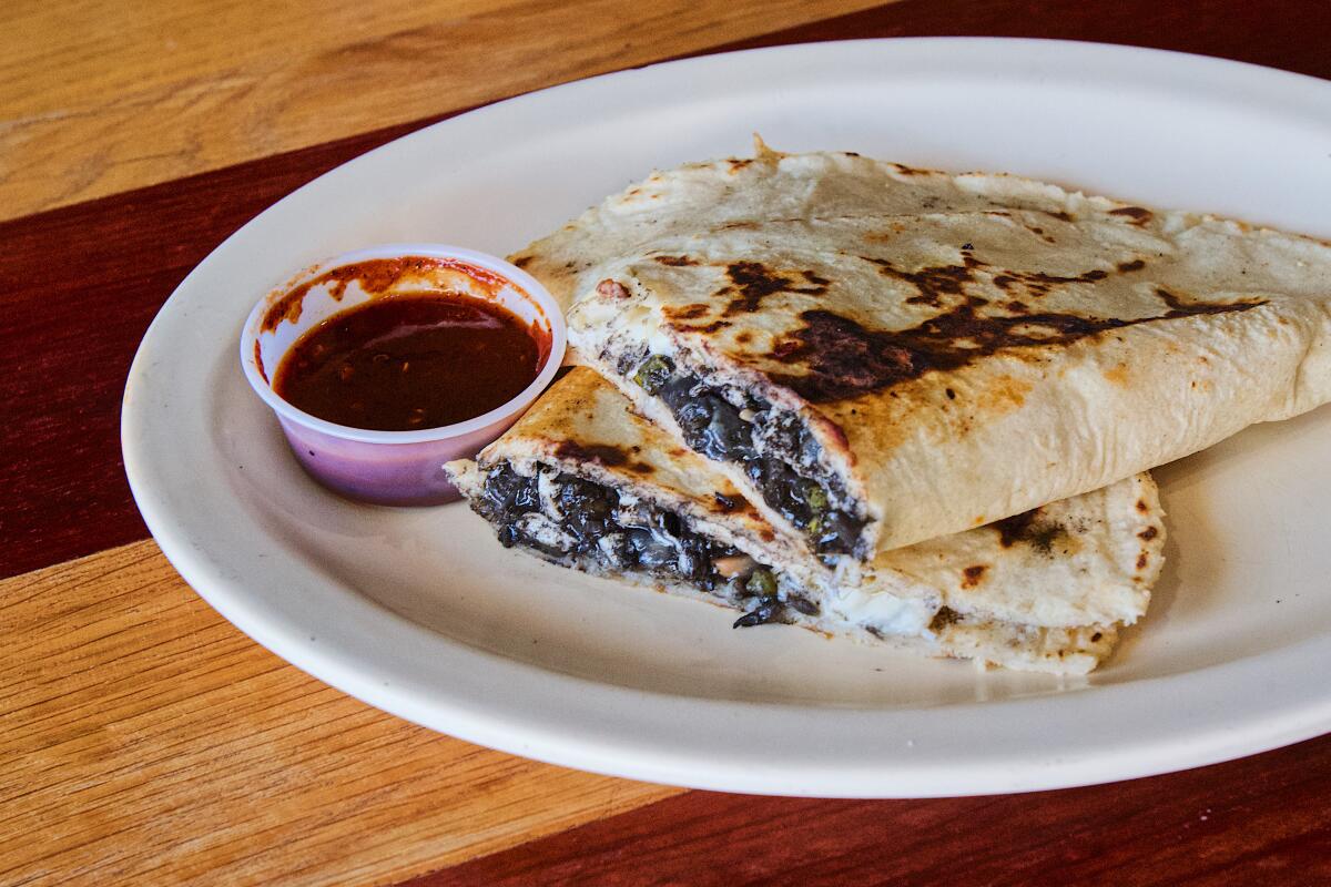 A massive Oaxacan empanada filled with huitlacoche, or corn smut, cut in half and served with salsa.