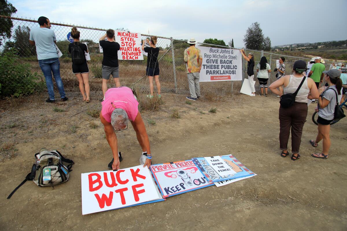 Protesters put signs on a fence demonstrating against the sale.