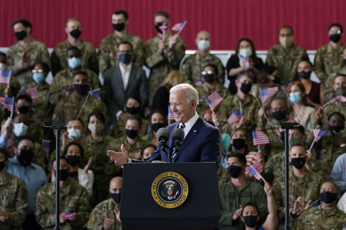 President Biden speaks at a lectern to a group of U.S. service members.