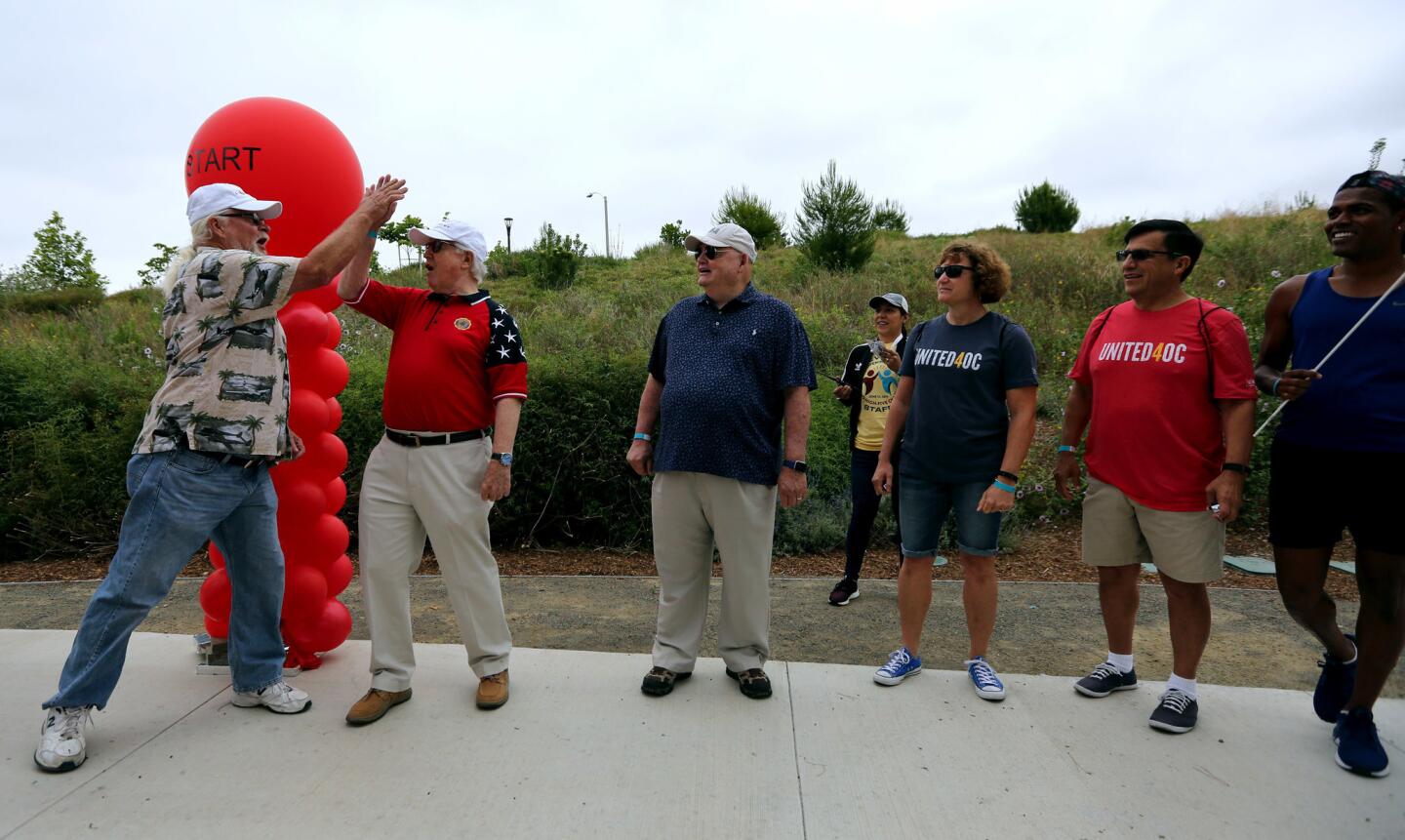 Retired member of the United States Marine Corps Bill Cook, of Mission Viejo, gives the first high-five to U.S. Army Vietnam veteran Robert Brower, of Irvine, to start a high-five chain to celebrate the grand opening of the Great Park Trails in Irvine on June 15, 2019. U.S. Army veteran John Rowe of Tustin stands to the right of Brower.
