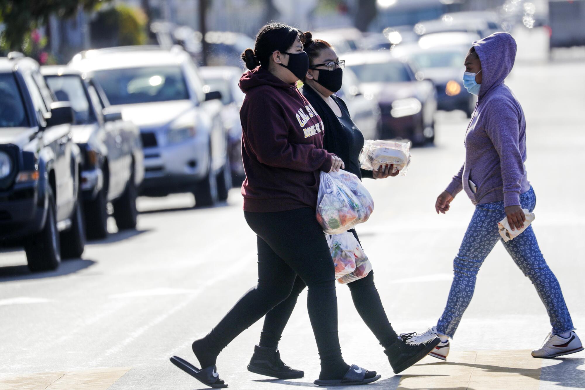 Women carry food bags from the Garfield High distribution site. 