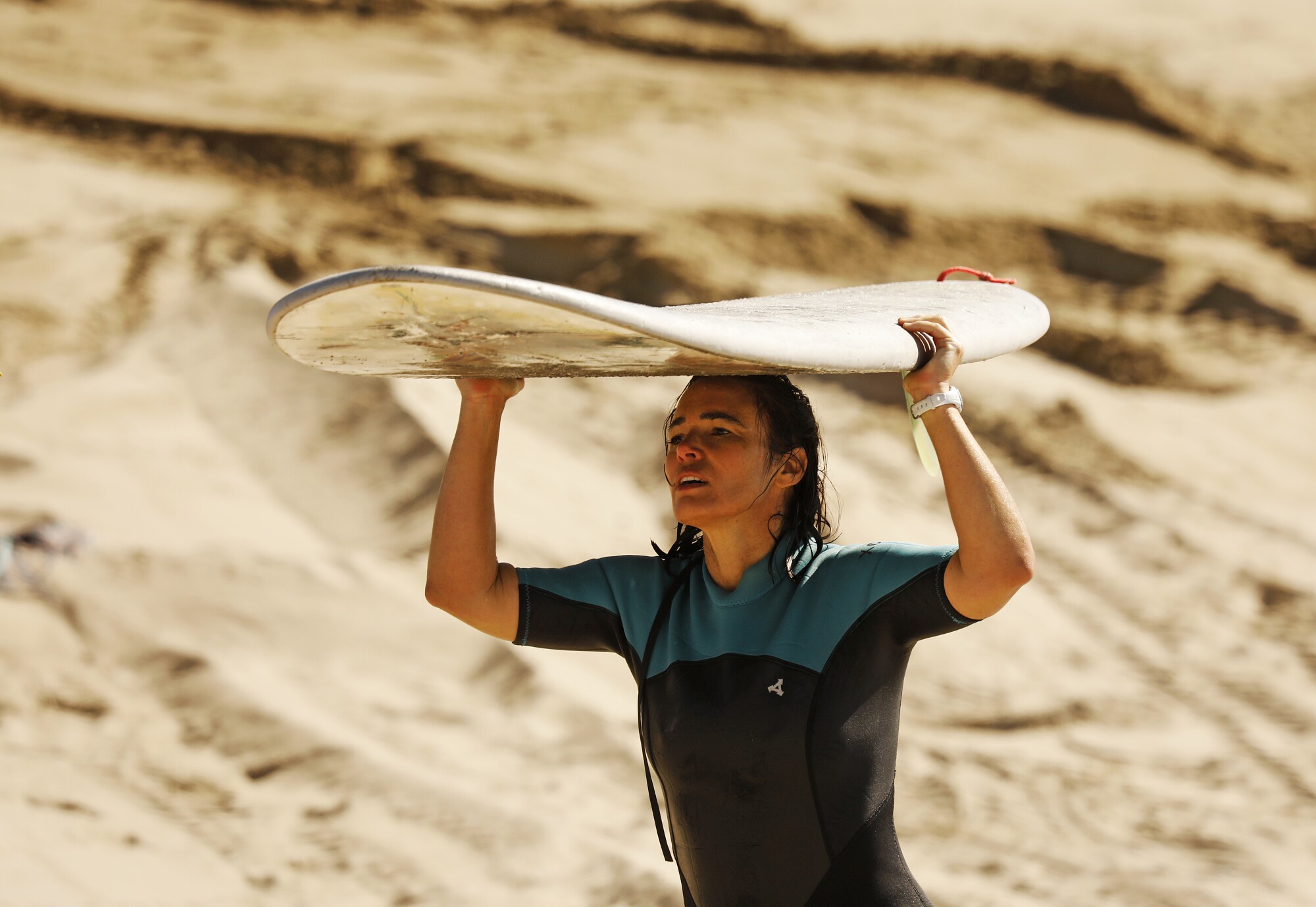 Natalia Folcini carries her surfboard at Surfrider Beach in Malibu.