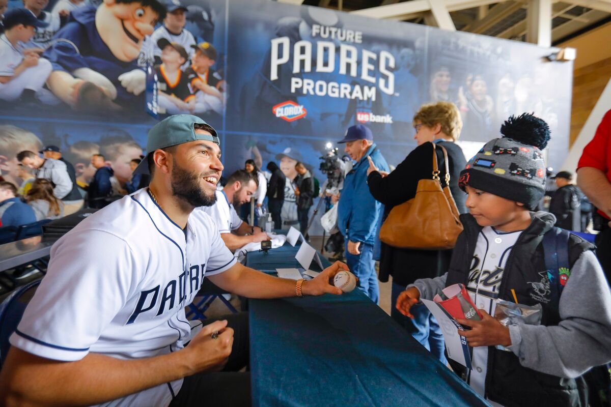Padres first baseman Eric Hosmer, left, is all smiles as he finishes signing an autograph on a baseball for eight-year-old Damain Quintana, right, from Orange County, during Padres FanFest 2019, at Petco Park.