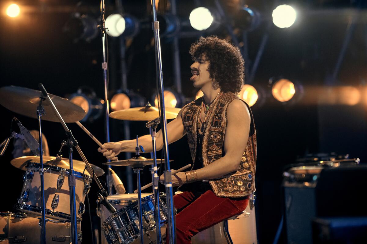 A man wearing a vest plays drums onstage in "Daisy Jones & the Six."