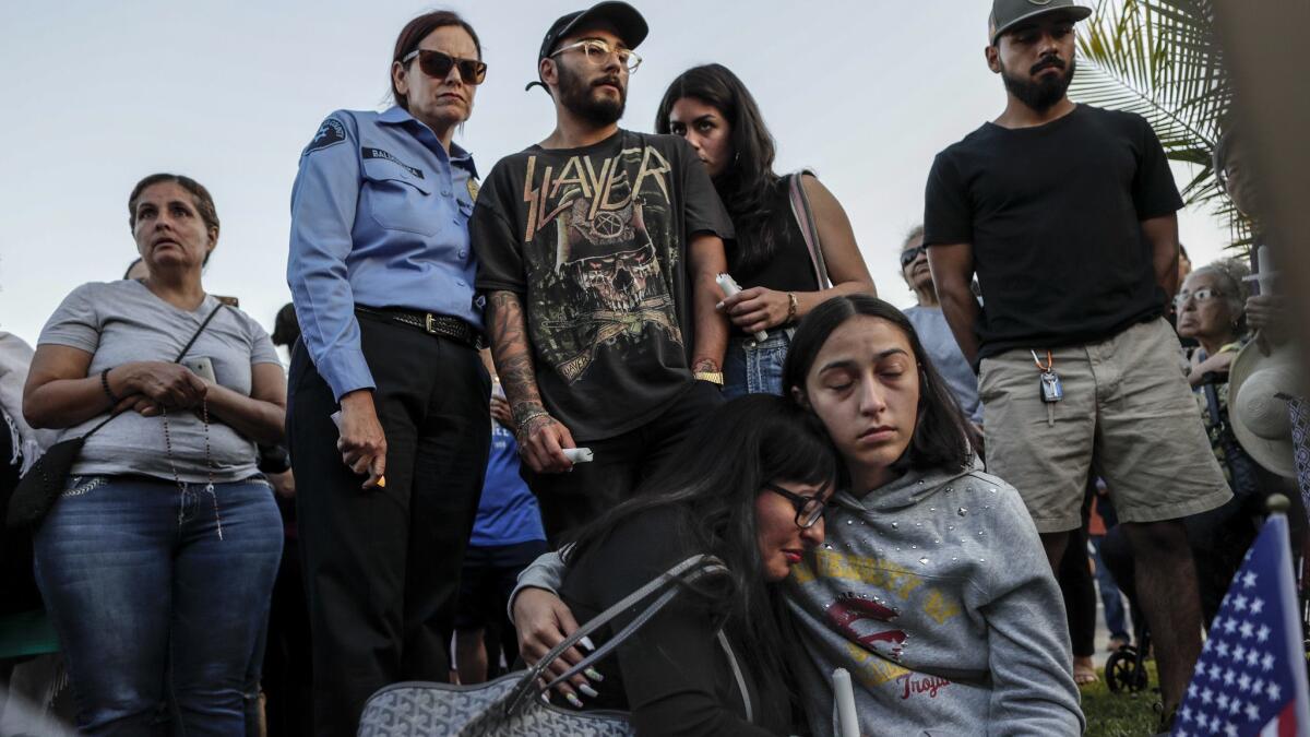 Deputy Joseph Solano's longtime girlfriend, Julianna Loza, front center, in black, is comforted by her daughter Jessica Jimenez at a vigil for their loved one. Solano's son Matthew, center, stands behind them.