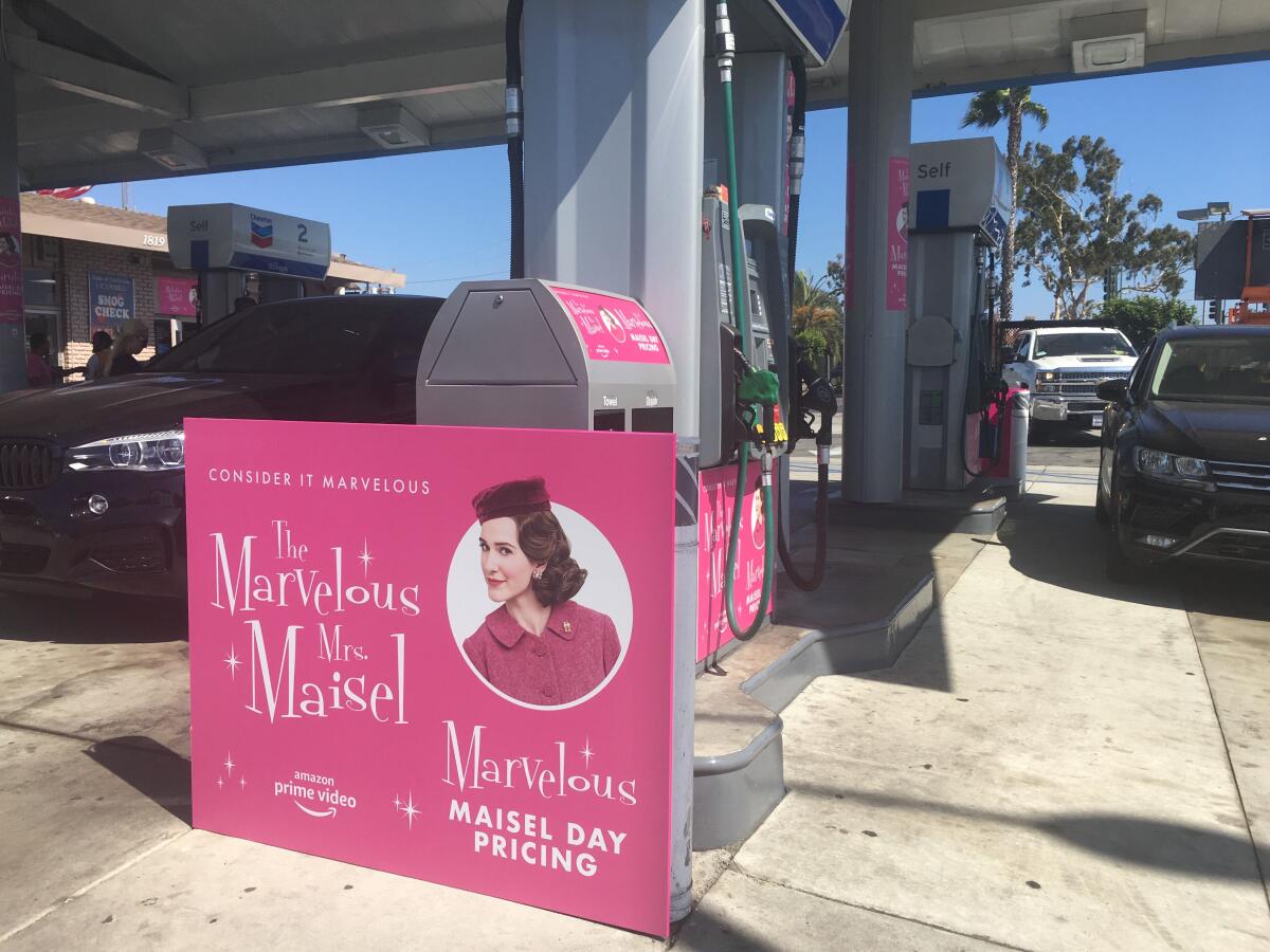 A "Maisel Day" promo poster at a Chevron gas station in Santa Monica.