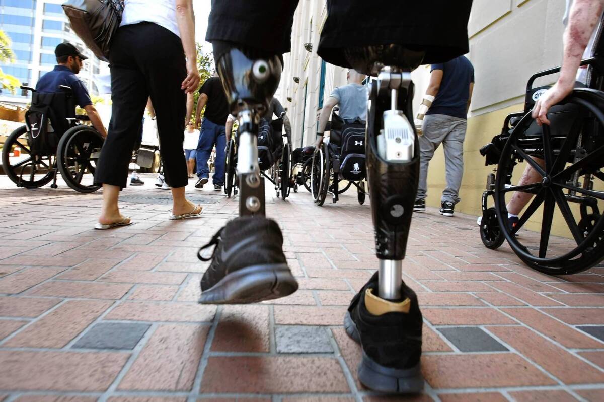 Combat veterans — some with prosthetic limbs, some in wheelchairs — go up Broadway Avenue in San Diego on an outing arranged by Naval Medical Center San Diego’s "community reentry" program.