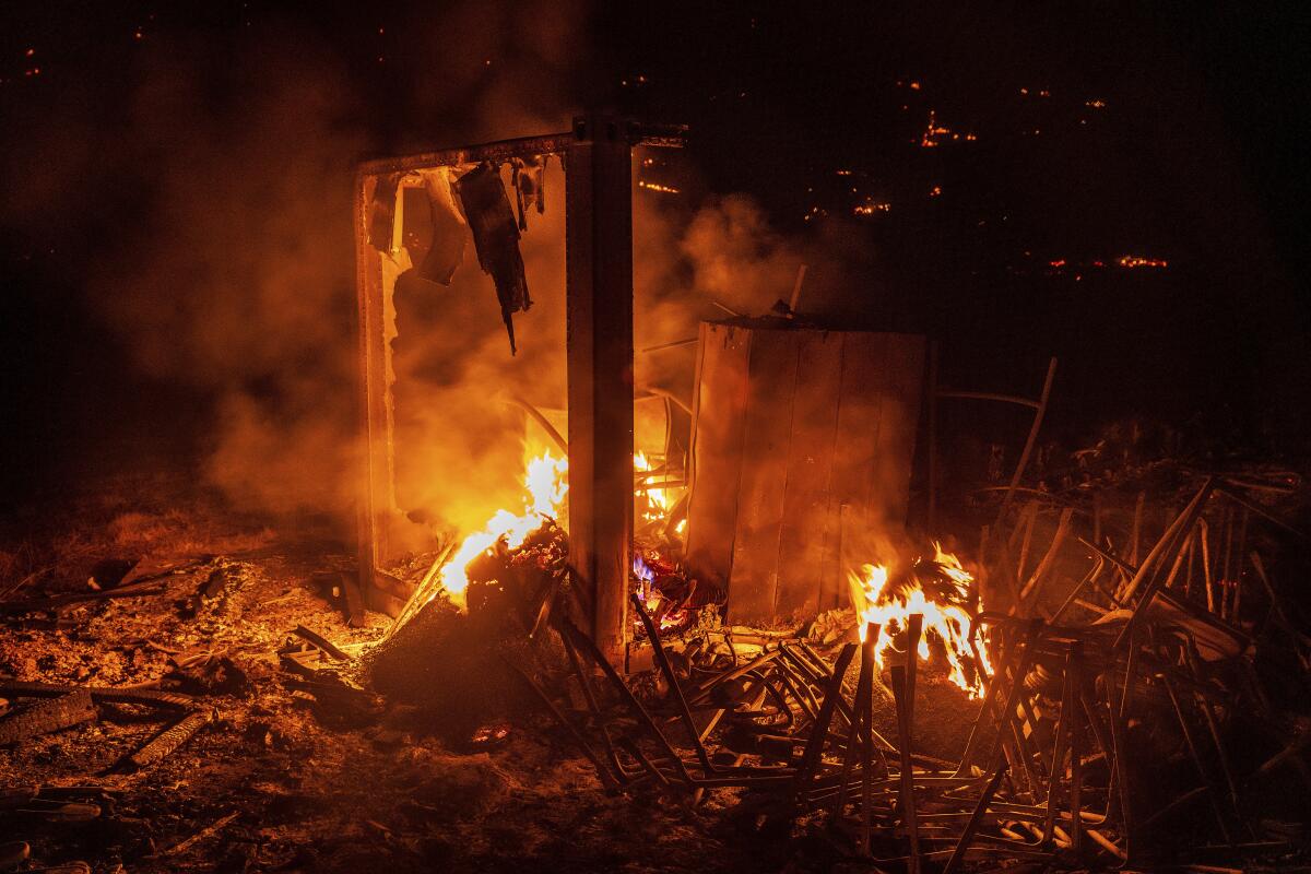 Flames from the French Fire consume a storage area at an athletic field in Mariposa.