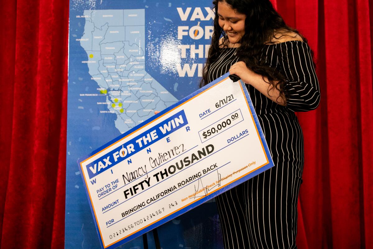 A teenage girl holds a giant check for $50,000.
