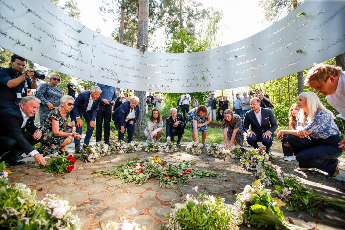 People in a wide circle kneel or stoop to place flowers on the ground.