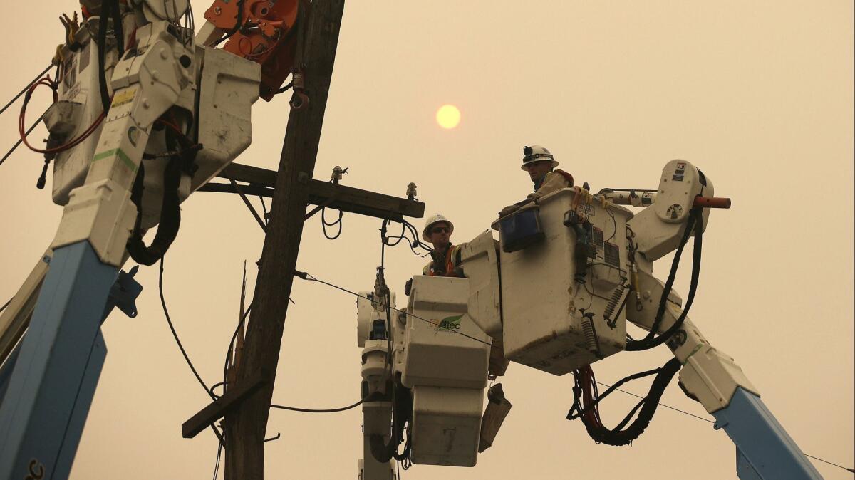 In this Nov. 9, 2018, file photo, Pacific Gas & Electric crews work to restore power lines in Paradise, Calif. PG&E and Southern California Edison are considering shutting off power to thousands of customers this week amid wildfire concerns.