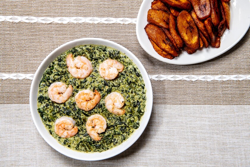 Ndolé in a white bowl beside a plate of plantains