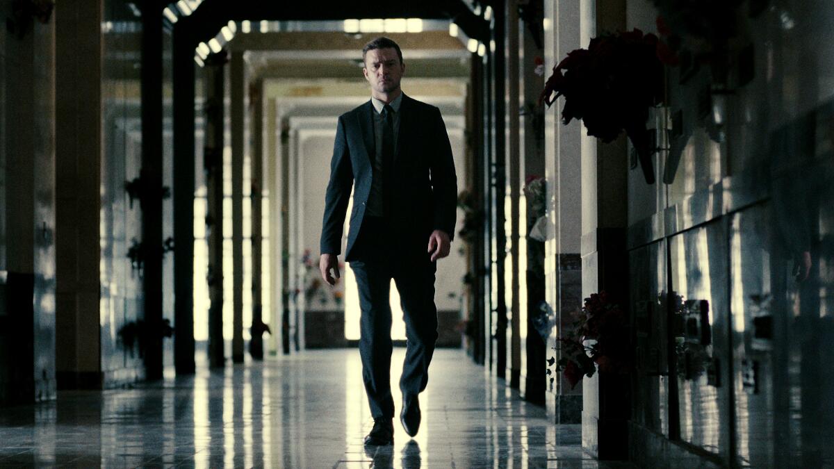 A man in a suit suit walks down a hallway.