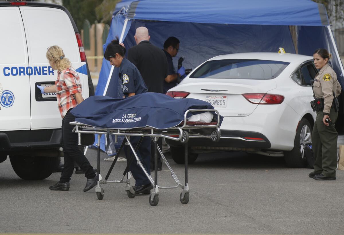 L.A. County Coroner officials remove the body of a man found in a white car parked in the street in front of the LAPD Southeast Community Police Station on West 108th Street in the Willowbrook area.