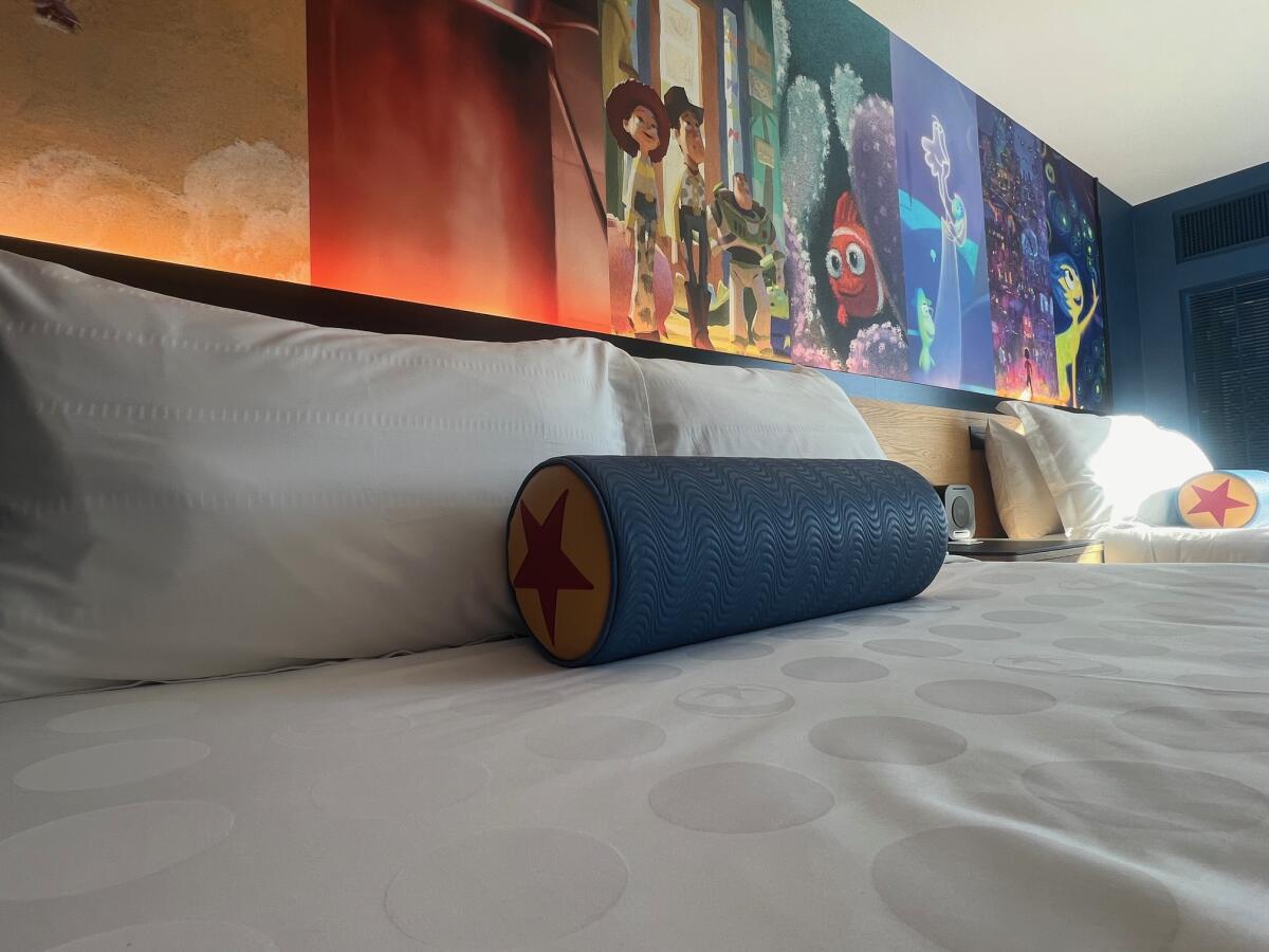 Above a bed sits a mural featuring scenes from various Pixar films. 
