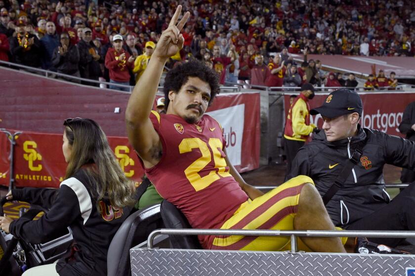 USC running back Travis Dye waves to the crowd while being taken off the field on a cart Nov. 11, 2022, at the Coliseum.