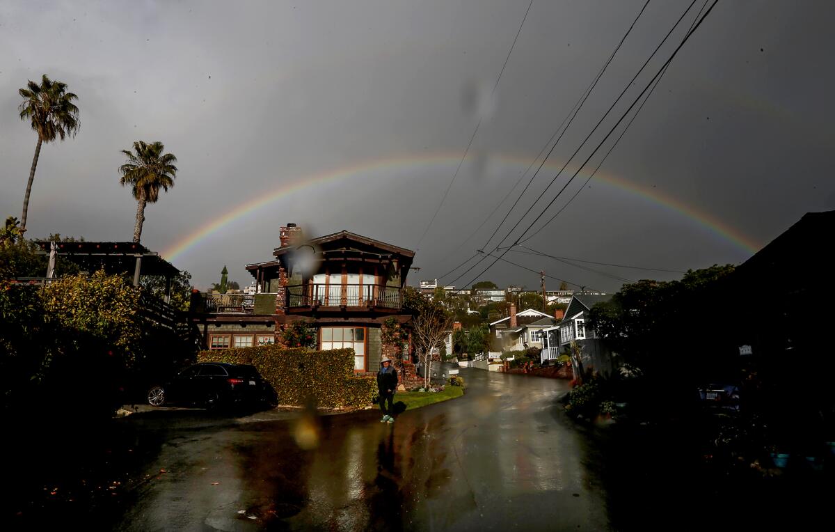 A full rainbow appears in a beam of sunlight as a rain storm flurry passes overhead on Lombardy Street in Laguna Beach.