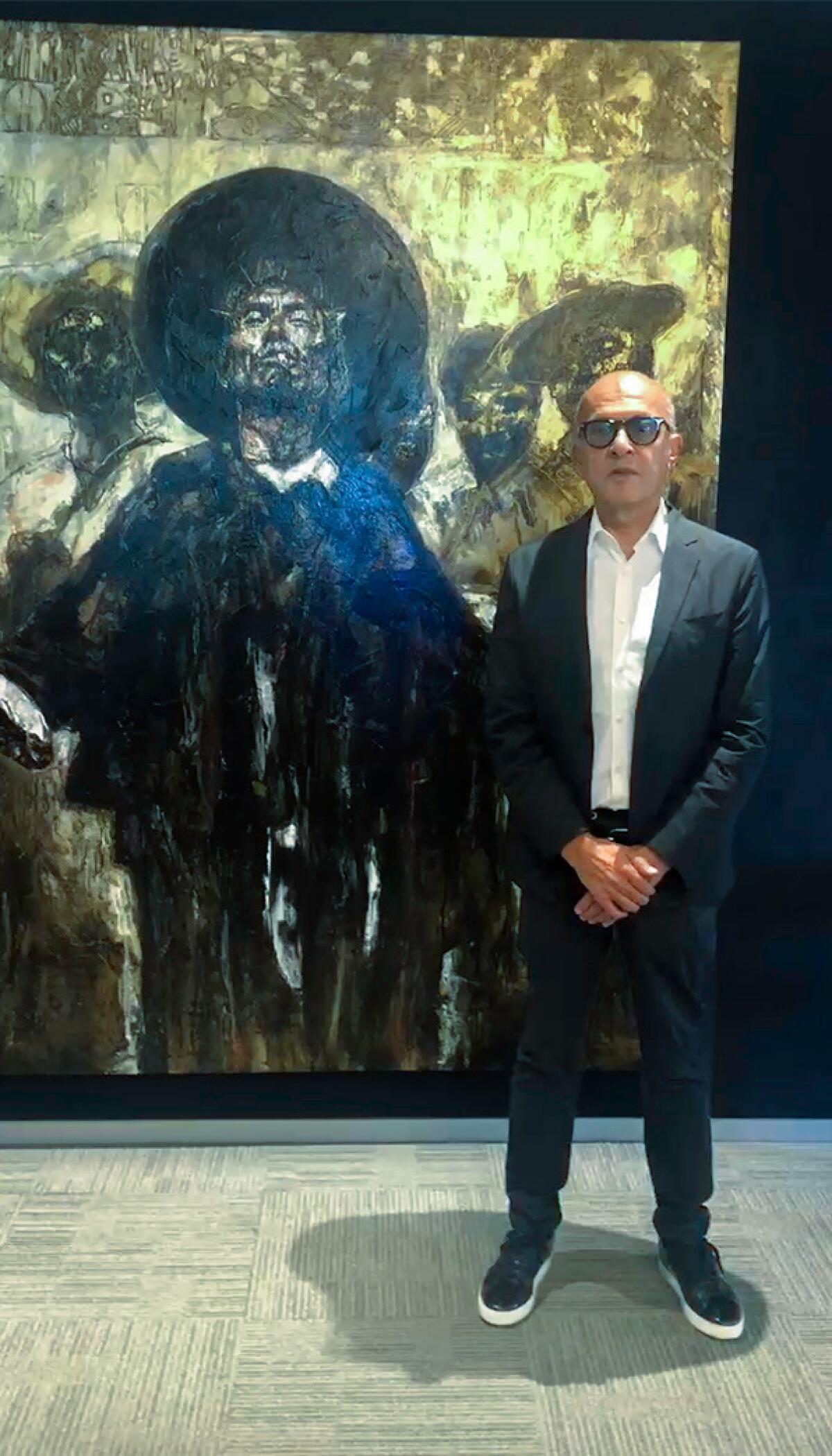 Walter Ulloa stands beside a painting.