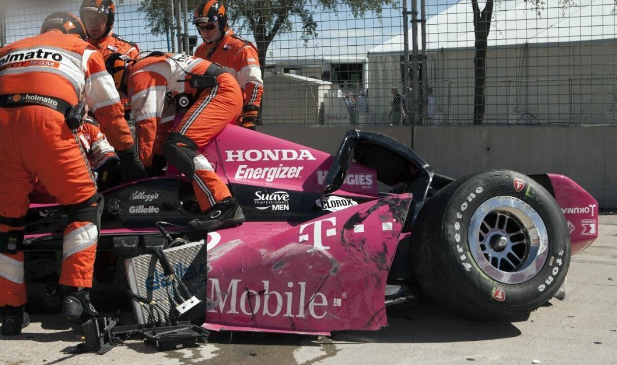 Workers remove Dario Franchitti from his wrecked car Sunday.