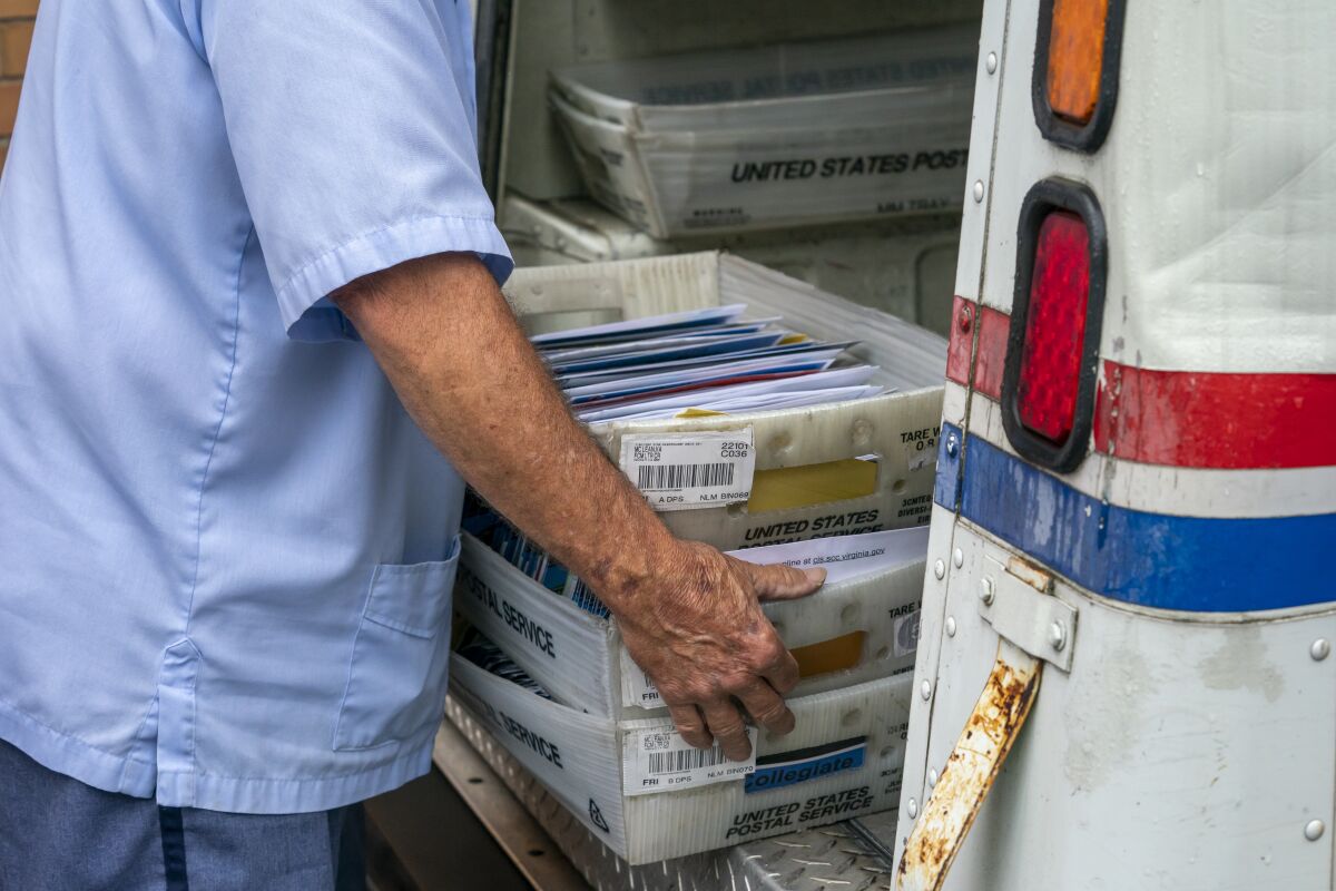 Letter carriers load mail trucks for deliveries at a U.S. Postal Service facility in McLean, Va.
