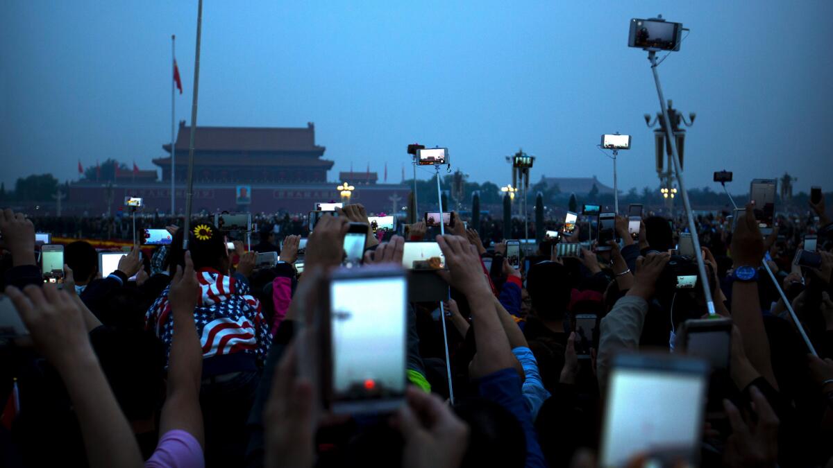 People take photos of the dawn flag-raising ceremony at Tiananmen Square on National Day in Beijing on Oct. 1.