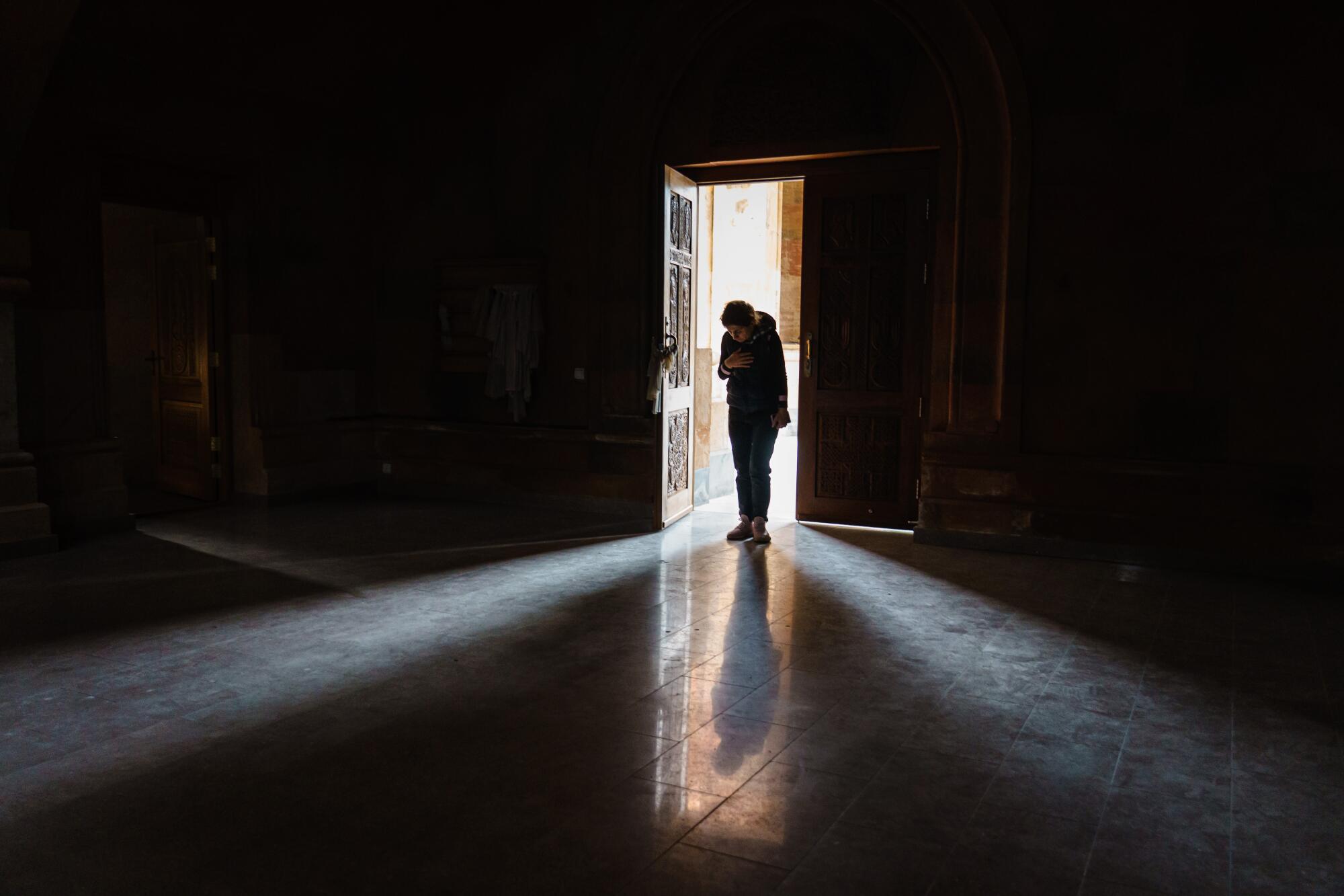 A woman bows her head in prayer before exiting the Holy Mother of God Cathedral.