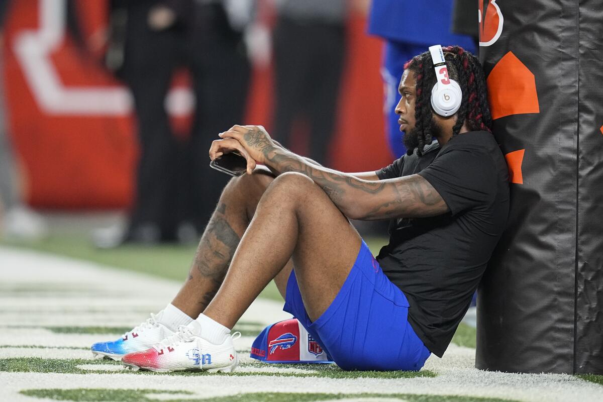 Damar Hamlin rests against a goalpost and wears headphones.