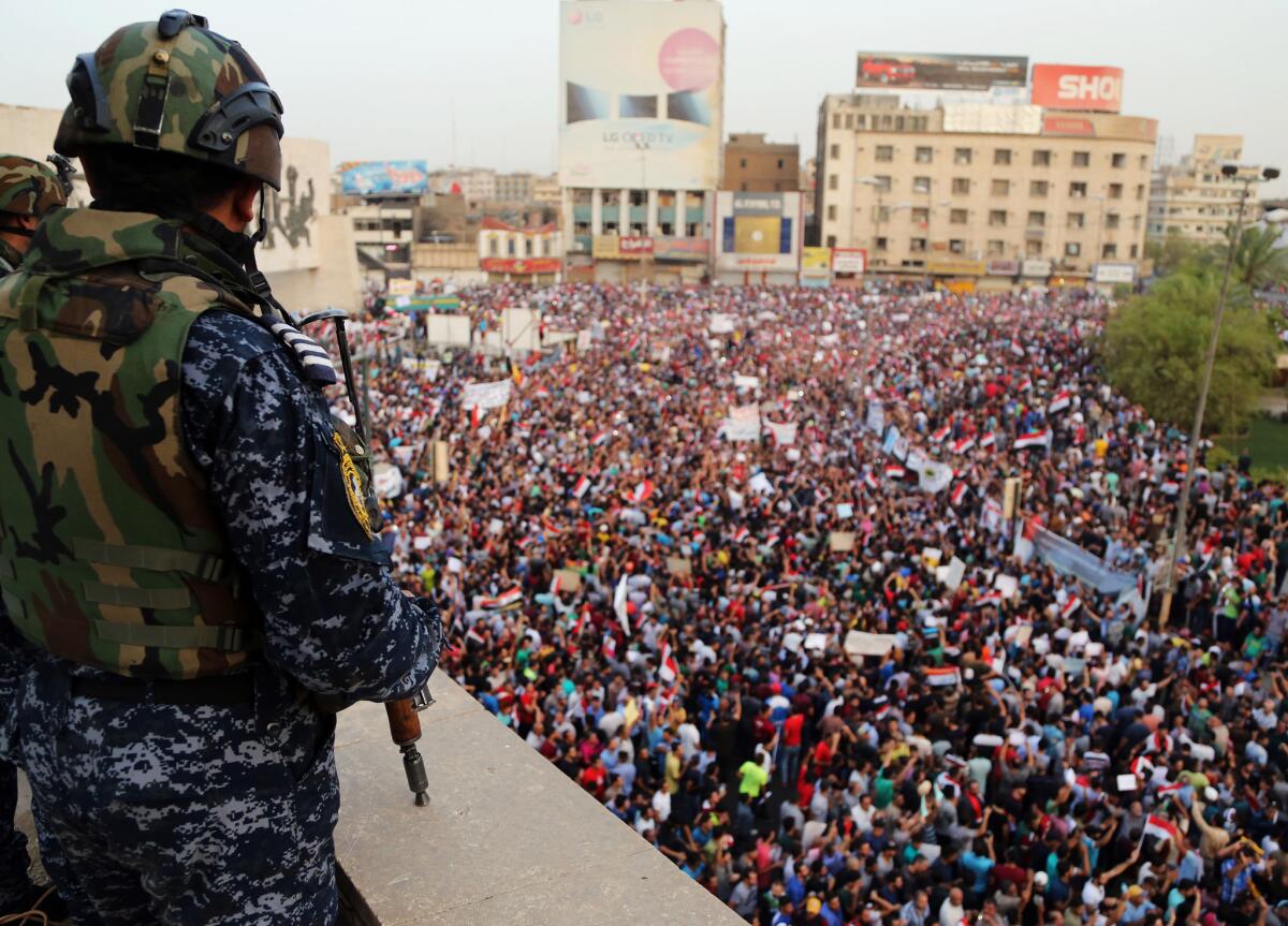 An Iraqi federal police officer stands guard as protesters, critical of government actions and expenditures, pack Tahrir Square in Baghdad on Friday.