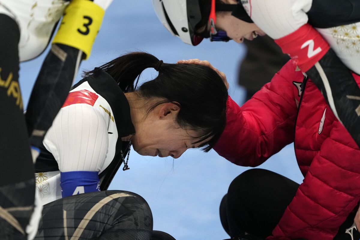 Nana Takagi of Team Japan is comforted by teammates after falling during the speedskating women's team pursuit finals at the 2022 Winter Olympics, Tuesday, Feb. 15, 2022, in Beijing. (AP Photo/Ashley Landis)