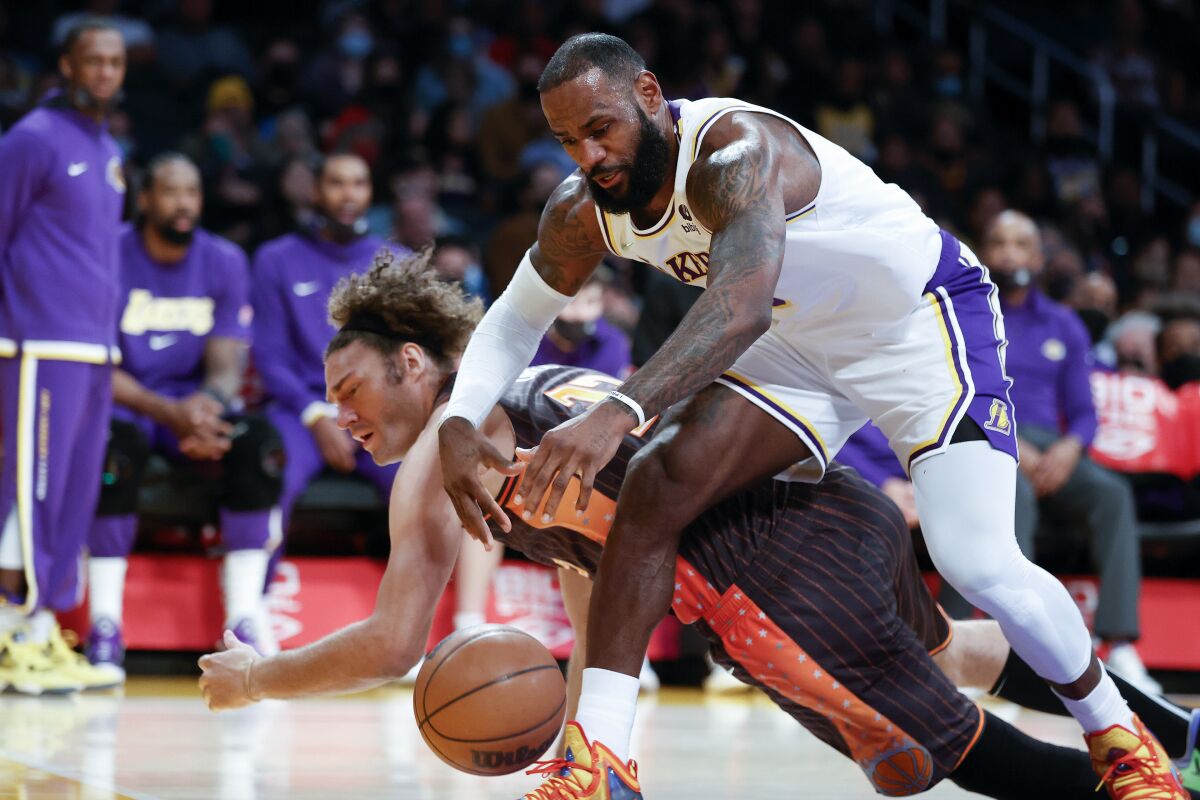 Los Angeles Lakers forward LeBron James, front, fights for a ball against Orlando Magic center Robin Lopez during the first half of an NBA basketball game in Los Angeles, Sunday, Dec. 12, 2021. (AP Photo/Ringo H.W. Chiu)