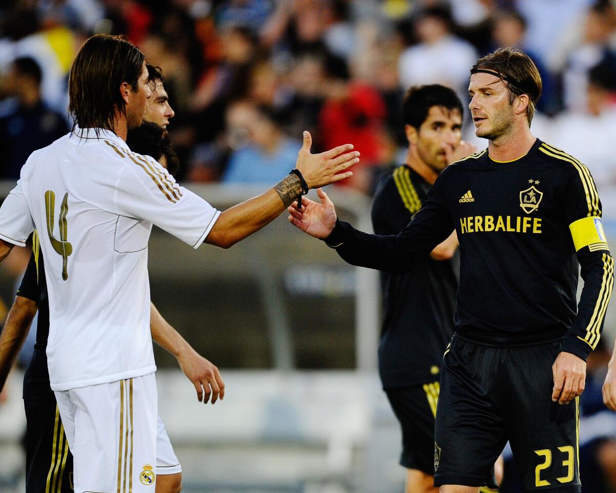 In 2011, David Beckham (23) of the Galaxy shakes hands with Sergio Ramos of Real Madrid at a match at the Herbalife World Football Challenge at the L.A. Memorial Coliseum.