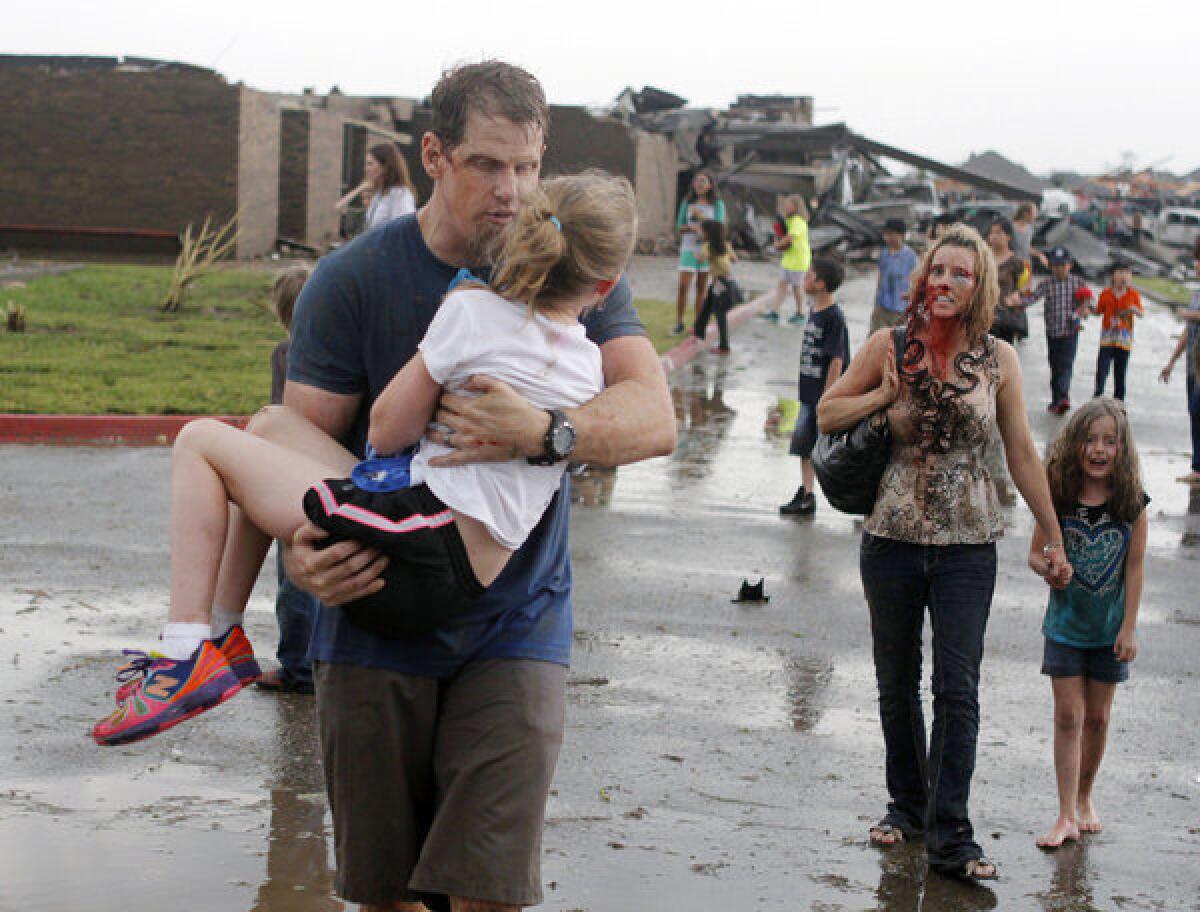 Teachers carry children away from Briarwood Elementary school after a tornado destroyed the school in south Oklahoma City.