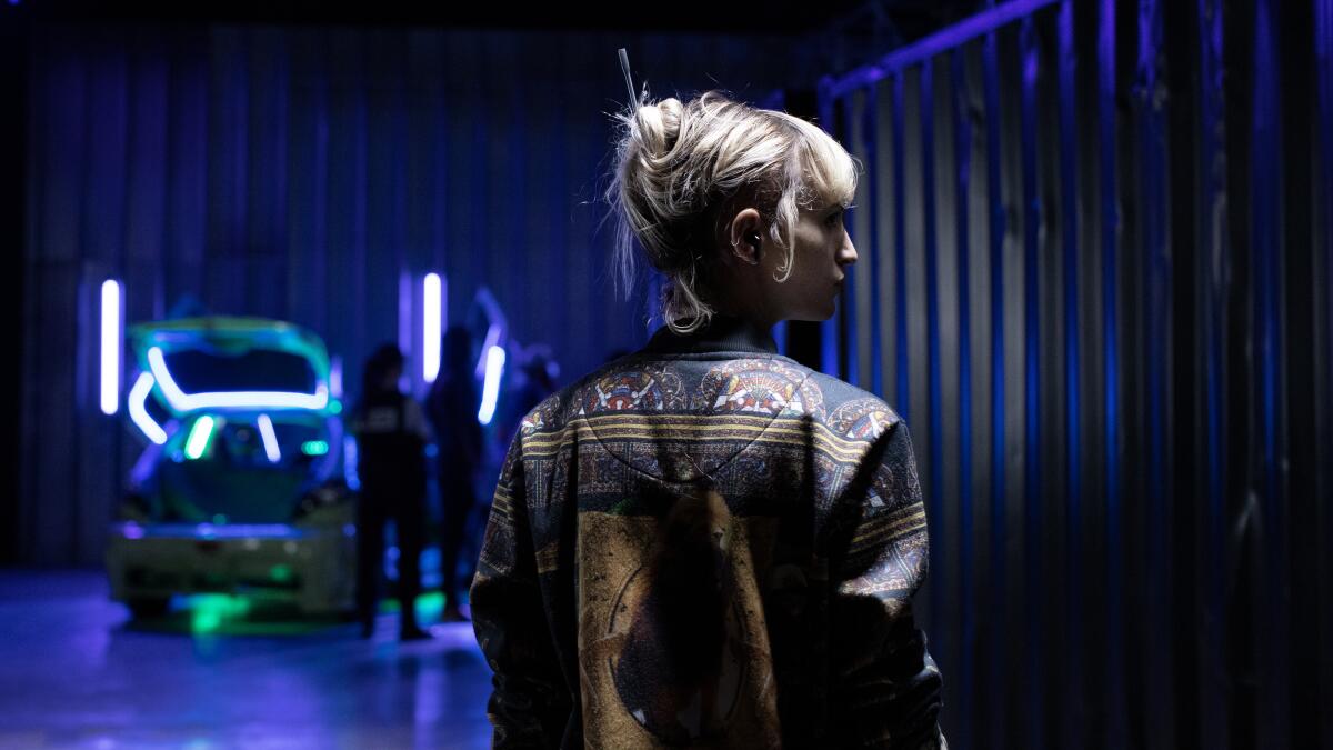A woman in a leather jacket in a dark room 