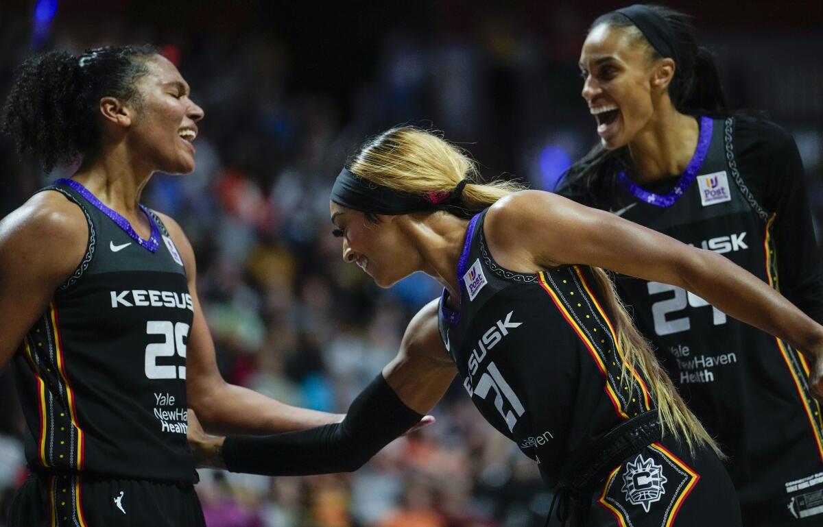 Alyssa Thomas, DiJonai Carrington and DeWanna Bonner of the Sun smile and interact during a game