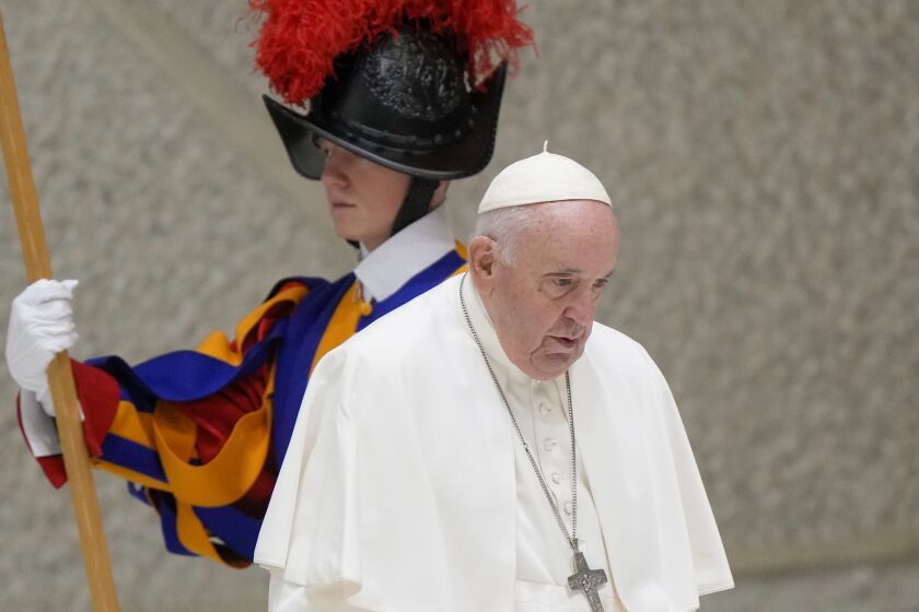 Pope Francis walks past a Vatican Swiss Guard as he arrives to meet with members of the Italian Schools for Peace Network in the Pope Paul VI hall at the Vatican, Monday, Nov. 28, 2022. (AP Photo/Andrew Medichini)