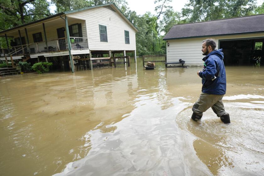 Clayton Lobue camina entre las aguas mientras se dirige a su casa, el viernes 3 de mayo de 2024, en New Caney, Texas. (Brett Coomer/Houston Chronicle vía AP)