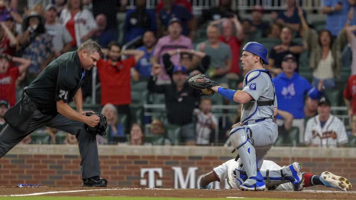 Will Smith has tagged Atlanta's Michael Harris II out at home plate in the third inning Monday.