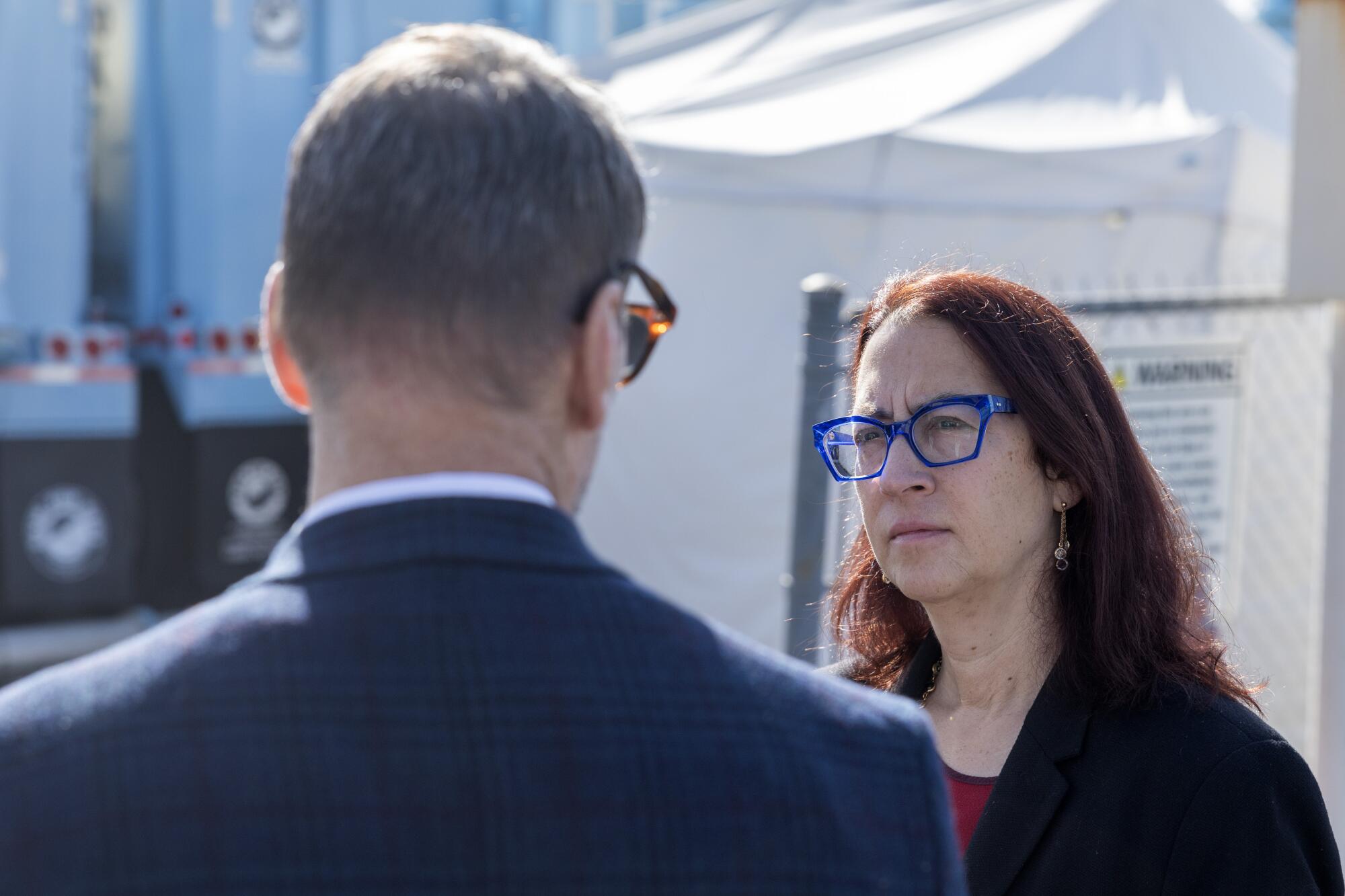 Assemblymember Laura Friedman, wearing blue glasses and speaking to a man who is turned away from the camera.