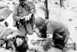 Medics treat a wounded U.S. soldier on D-Day during the Normandy landings in Nazi-occupied France.