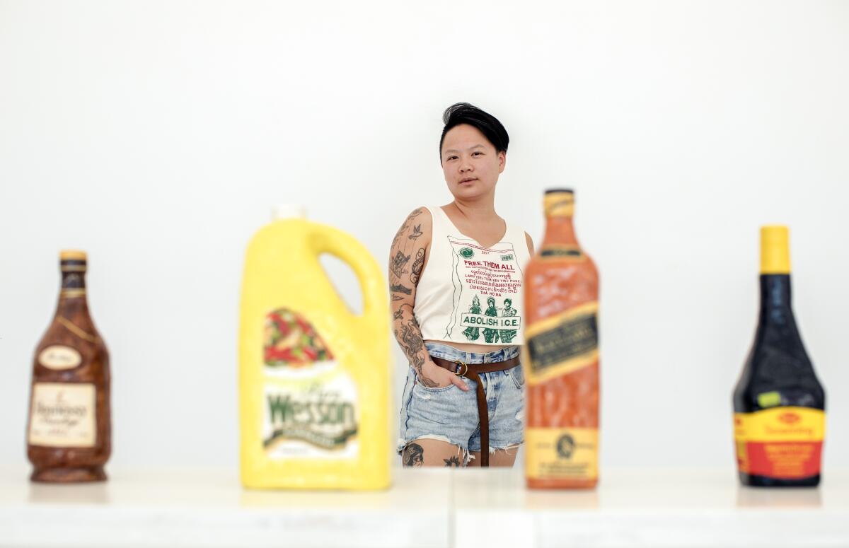 An artist stands behind her art pieces displayed on a table.